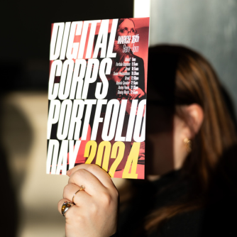 Woman holding flier describing Digital Corps' Portfolio Day 2024